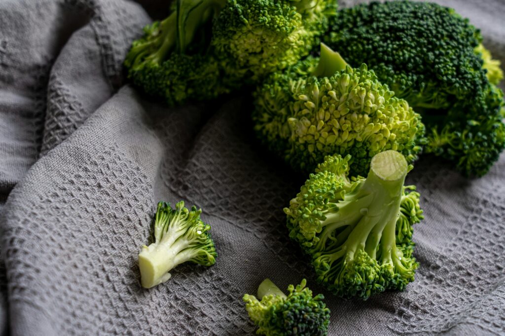 Vibrant green broccoli florets displayed on a gray textured cloth for a fresh, organic feel.